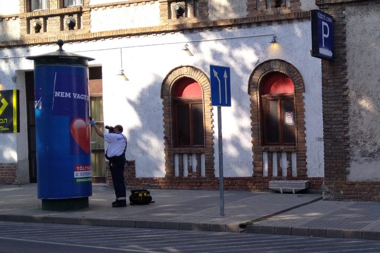 Olyan jó a közbiztonság, hogy a pécsi rendőröknek már csak a kormányzati plakát átragasztásával kell foglalkoznia?